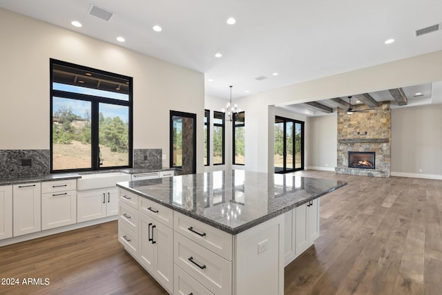 kitchen featuring a wealth of natural light, a center island, dark hardwood / wood-style floors, and dark stone countertops