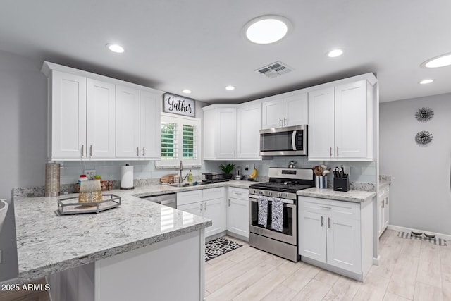 kitchen with light stone counters, visible vents, decorative backsplash, appliances with stainless steel finishes, and white cabinetry