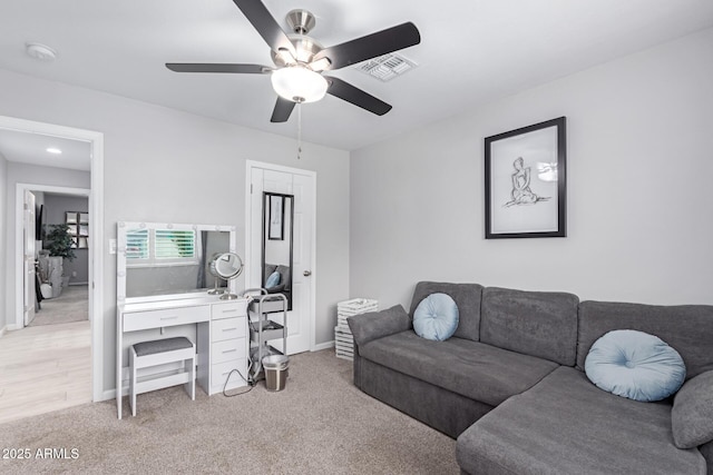 living room with light carpet, visible vents, baseboards, and a ceiling fan