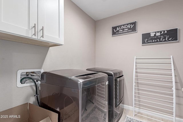 laundry room featuring separate washer and dryer, cabinet space, and baseboards