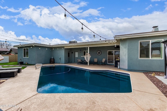 pool with a patio, central AC, and fence