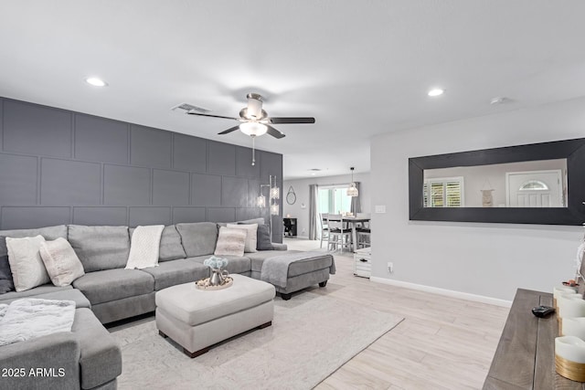 living area with a ceiling fan, baseboards, visible vents, an accent wall, and light wood-type flooring