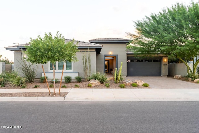 view of front facade with an attached garage, fence, driveway, a tiled roof, and stucco siding