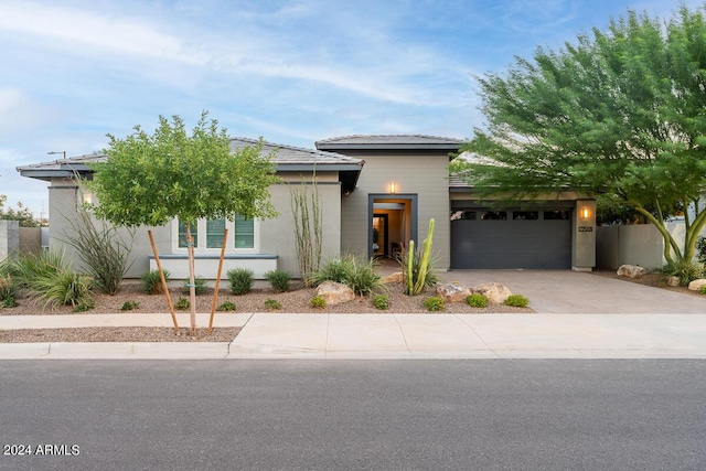 view of front of house with a garage, driveway, fence, and stucco siding