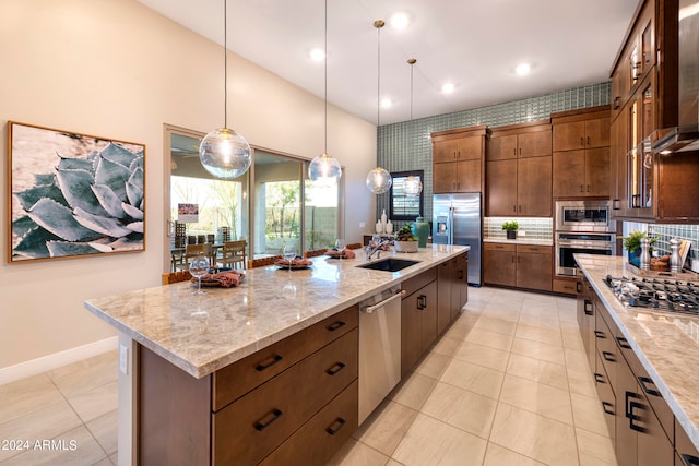 kitchen with tasteful backsplash, appliances with stainless steel finishes, light tile patterned floors, sink, and a center island with sink