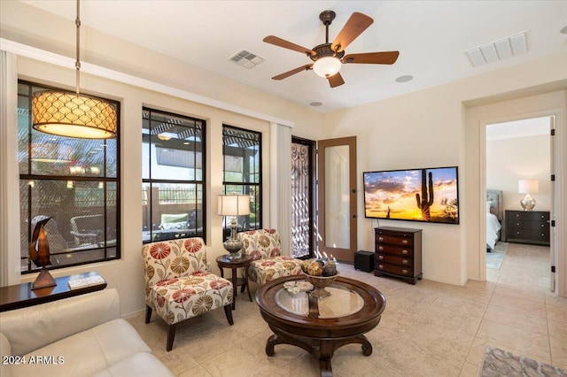 living area with light tile patterned floors and ceiling fan