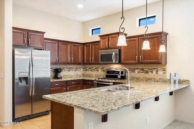 kitchen featuring sink, stainless steel appliances, decorative light fixtures, and kitchen peninsula