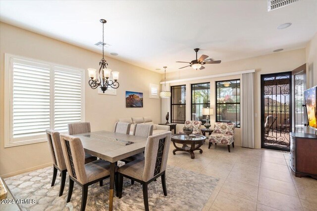 dining space with ceiling fan with notable chandelier and light tile patterned floors