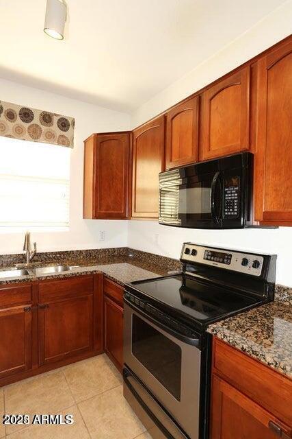 kitchen featuring sink, light tile patterned floors, dark stone counters, and stainless steel range with electric cooktop