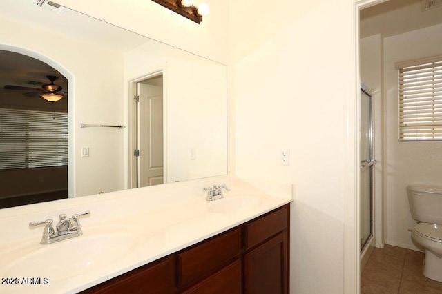 bathroom featuring a shower with door, tile patterned floors, ceiling fan, toilet, and vanity