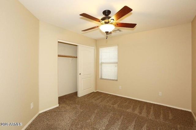 unfurnished bedroom featuring ceiling fan, a closet, and dark colored carpet