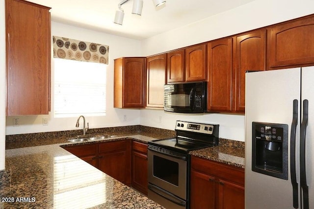 kitchen with sink, dark stone countertops, track lighting, and appliances with stainless steel finishes