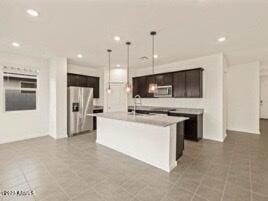 kitchen with dark brown cabinetry, stainless steel appliances, an island with sink, and hanging light fixtures