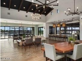 dining area featuring a healthy amount of sunlight, a notable chandelier, high vaulted ceiling, and beamed ceiling