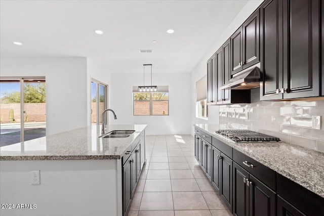 kitchen with stainless steel gas stovetop, sink, a kitchen island with sink, and decorative light fixtures