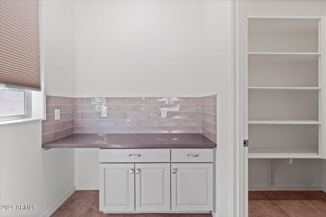 kitchen featuring white cabinets, light tile patterned flooring, and backsplash