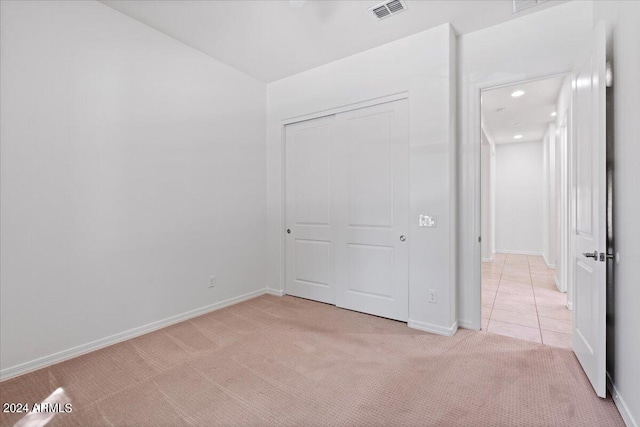 unfurnished bedroom featuring light carpet and a closet