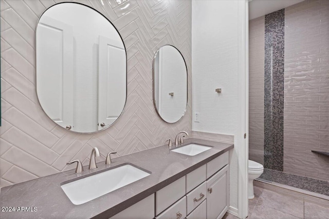 11856 W Lone Tree Trl, Peoria, AZ 85383 - bathroom featuring toilet, double vanity, a tile shower, decorative backsplash, and tile patterned flooring