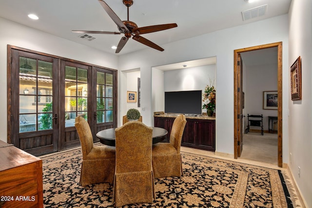 dining space with ceiling fan, light carpet, and french doors