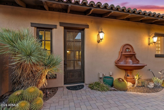 exterior entry at dusk featuring a patio area