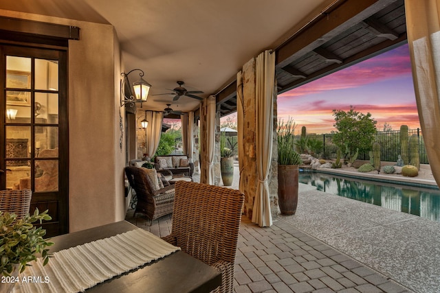 patio terrace at dusk with ceiling fan and a fenced in pool