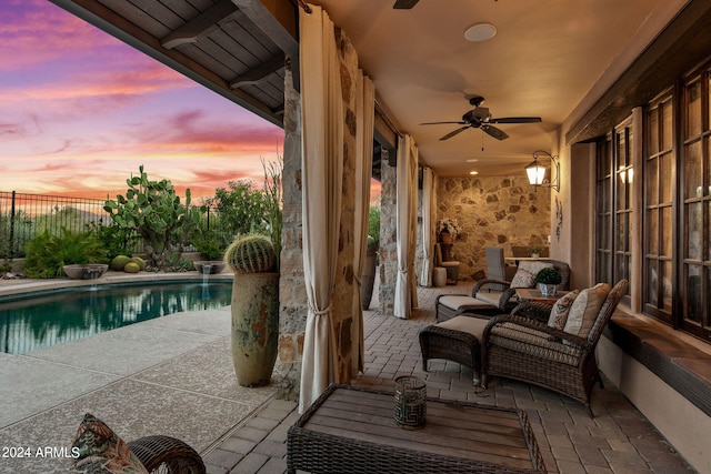 patio terrace at dusk with a fenced in pool and ceiling fan