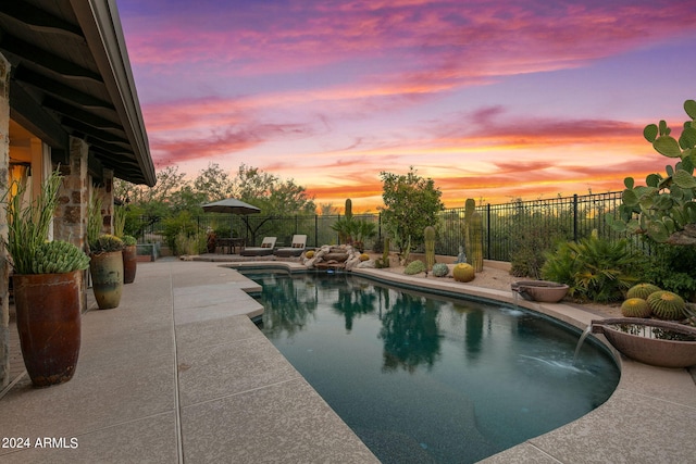 pool at dusk with a patio and pool water feature