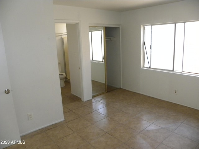 unfurnished bedroom with ensuite bath and a closet