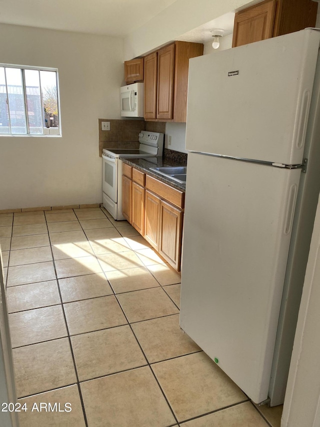 kitchen with light tile patterned flooring, sink, and white appliances