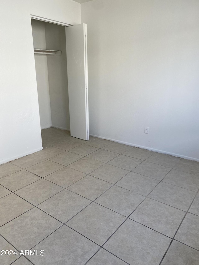 unfurnished bedroom featuring light tile patterned flooring and a closet