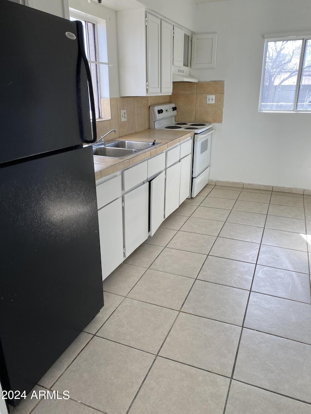 kitchen featuring white cabinets, sink, black fridge, extractor fan, and white range with electric cooktop