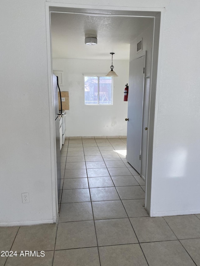 hallway featuring tile patterned floors and a textured ceiling