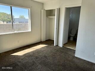 unfurnished bedroom with dark colored carpet and multiple windows