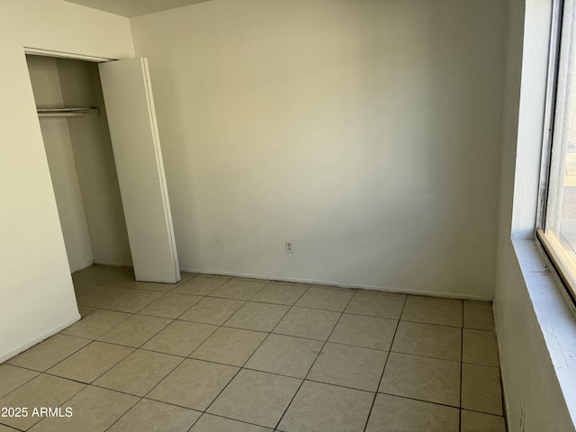 unfurnished bedroom featuring light tile patterned floors and a closet