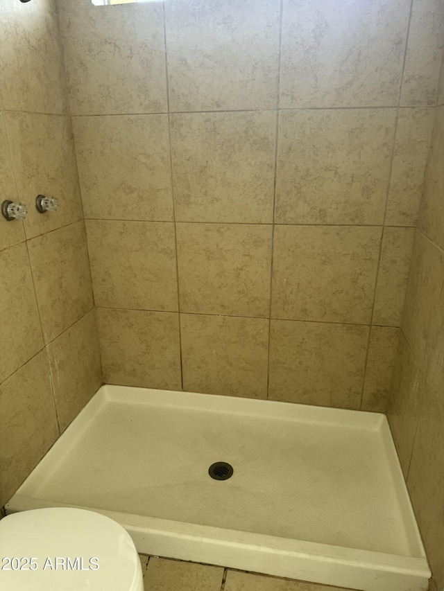 bathroom featuring tiled shower and toilet