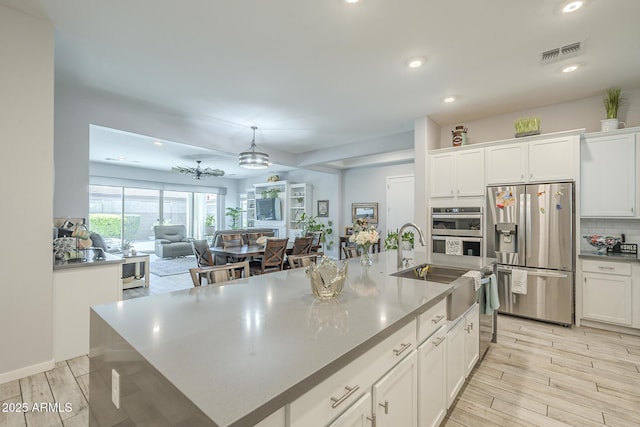 17253 W Echo Ln, Waddell, AZ 85355 - kitchen featuring appliances with stainless steel finishes, white cabinets, tasteful backsplash, recessed lighting, and a center island with sink