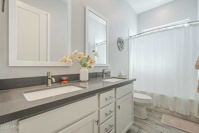 17253 W Echo Ln, Waddell, AZ 85355 - full bathroom featuring toilet, double vanity, wood finished floors, and shower / bathtub combination with curtain