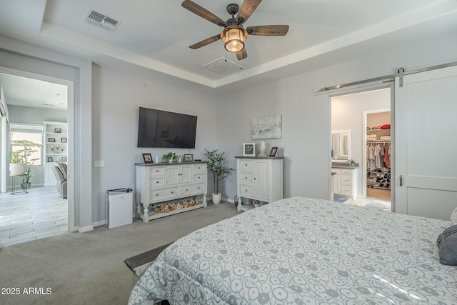 17253 W Echo Ln, Waddell, AZ 85355 - carpeted bedroom with a barn door, a tray ceiling, a spacious closet, baseboards, and ceiling fan