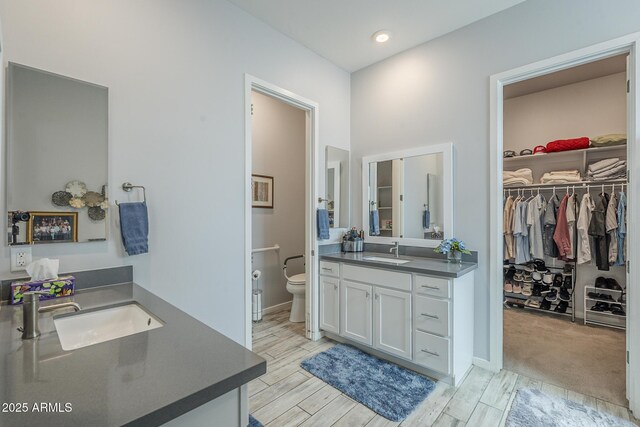 17253 W Echo Ln, Waddell, AZ 85355 - full bath with two vanities, toilet, a walk in closet, and wood finish floors