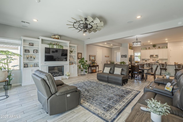17253 W Echo Ln, Waddell, AZ 85355 - living area featuring light wood-type flooring, recessed lighting, and a glass covered fireplace