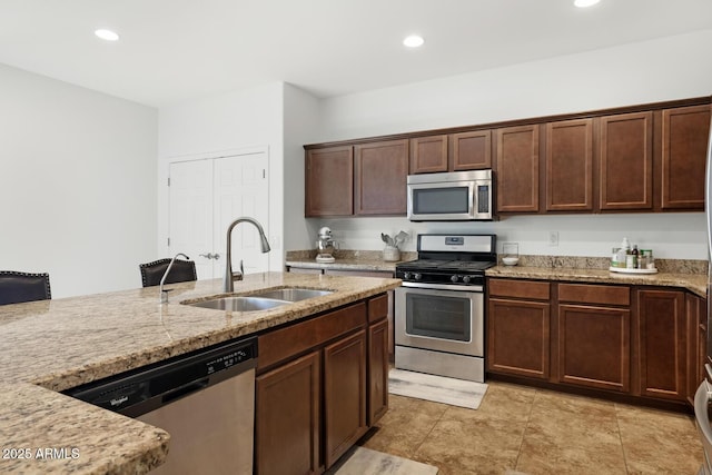 kitchen with appliances with stainless steel finishes, light stone counters, and sink