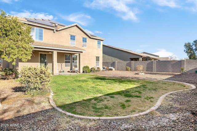 back of property with a lawn and solar panels