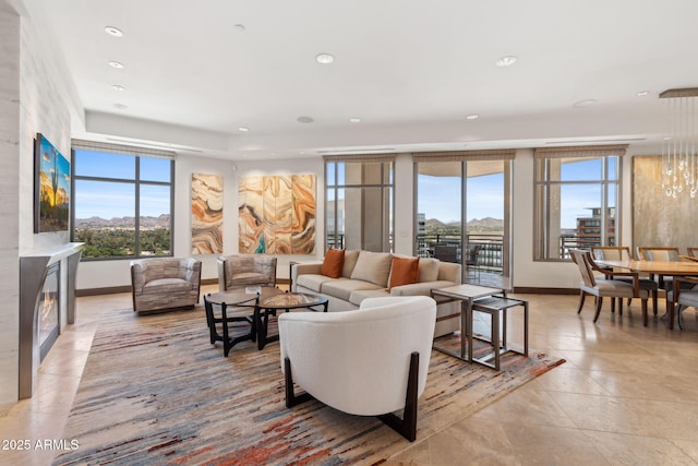 living room featuring baseboards, recessed lighting, light tile patterned floors, a glass covered fireplace, and a mountain view