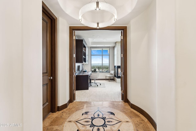 hallway featuring baseboards and an office area