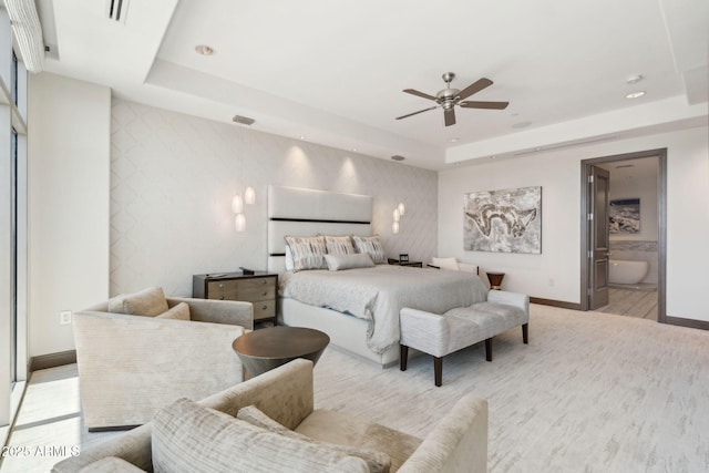 bedroom featuring baseboards, a raised ceiling, ensuite bathroom, a ceiling fan, and wallpapered walls