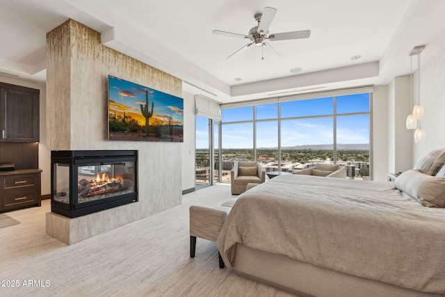bedroom featuring a multi sided fireplace, access to outside, a wall of windows, ceiling fan, and light wood-style flooring