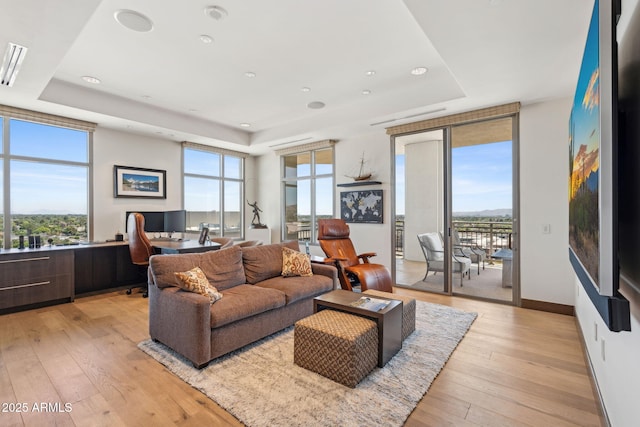 living area with a raised ceiling, a desk, light wood-style flooring, baseboards, and recessed lighting