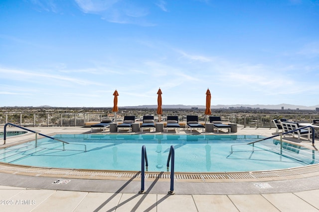 community pool with a mountain view, fence, and a patio