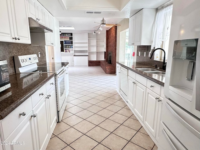 kitchen with ceiling fan, white cabinets, a brick fireplace, and white appliances