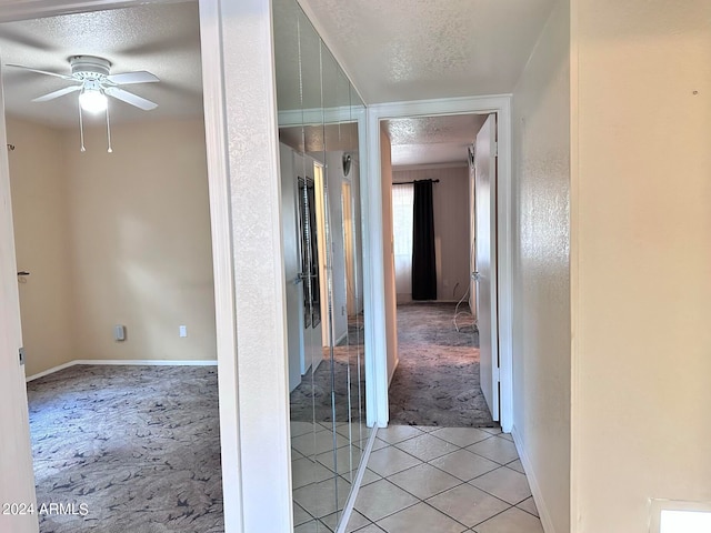 hallway with a textured ceiling and light tile patterned floors